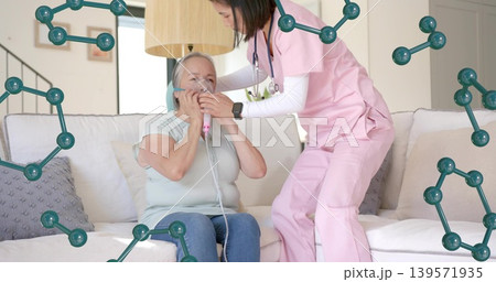 Helping nurse in pink scrubs stethoscope leaning toward patient on sofa at home, adjusting mask 139571935