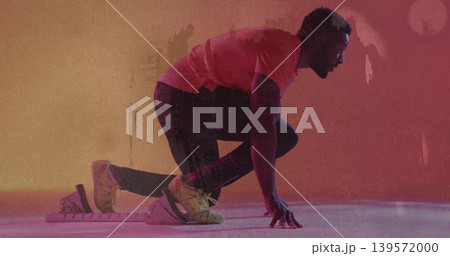 Poising athlete in leggings crouching in studio with block and strapped shoes, magenta orange light Poising athlete in leggings crouching in studio with block and strapped shoes, magenta orange light 139572000