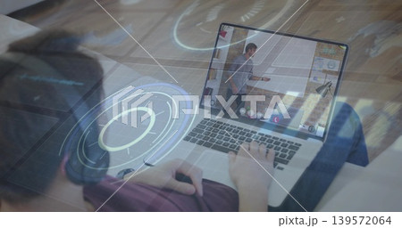 Using laptop on sofa teen wearing over-ear headset viewing host gesturing on screen holograms Using laptop on sofa teen wearing over-ear headset viewing host gesturing on screen holograms 139572064