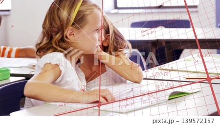 Sitting girl in white top yellow headband leaning toward classmate in class, papers, red math grid Sitting girl in white top yellow headband leaning toward classmate in class, papers, red math grid 139572157