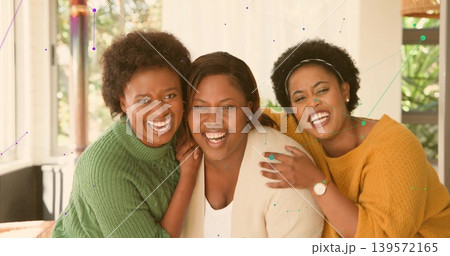 Smiling three mid adult women wearing knit sweaters leaning closely on couch, showing rings 139572165