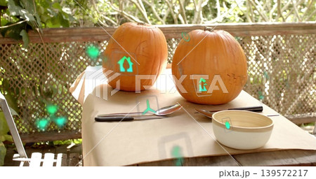 Sitting two orange pumpkins showing stencil marks on kraft-covered patio table, with green AR icons 139572217