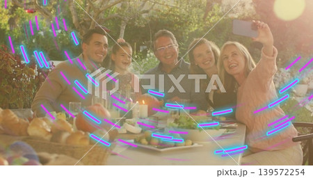 Taking family selfie, five people leaning in at backyard table, in sweaters, holding smartphone Taking family selfie, five people leaning in at backyard table, in sweaters, holding smartphone 139572254