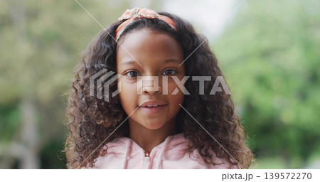 Looking girl with curly hair speaking at park, wearing light pink zip-up hoodie and headband Looking girl with curly hair speaking at park, wearing light pink zip-up hoodie and headband 139572270