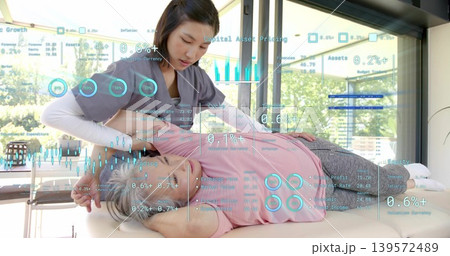 Applying therapist wearing grey top adjusting client in pink top on clinic table, AR overlays shown 139572489