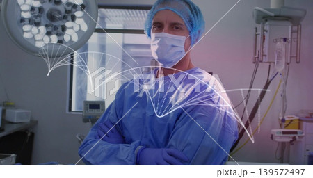 Standing surgeon wearing blue gown, cap, mask and gloves in operating room with waveform overlay Standing surgeon wearing blue gown, cap, mask and gloves in operating room with waveform overlay 139572497