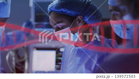 Operating lead surgeon focusing in OR, wearing blue cap, face mask, gown, red DNA overlay 139572503