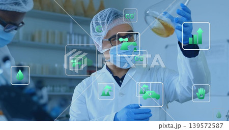 Female scientist inspecting Erlenmeyer flask with amber sample in lab, in PPE and green overlays 139572587