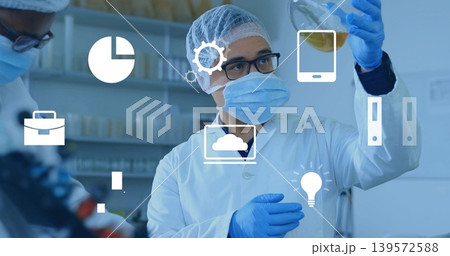 Inspecting male technician wearing PPE holding amber flask to eye level in lab with overlay icons Inspecting male technician wearing PPE holding amber flask to eye level in lab with overlay icons 139572588