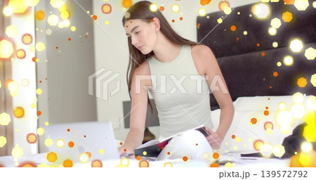Typing woman in sleeveless top, light pants using laptop on white bed with notebook pen, bokeh Typing woman in sleeveless top, light pants using laptop on white bed with notebook pen, bokeh 139572792