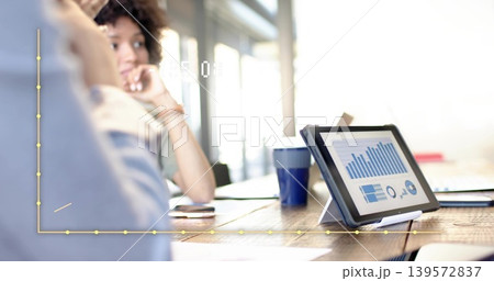 Displaying tablet on stand at meeting table, colleagues in blue shirt discussing charts, copy space Displaying tablet on stand at meeting table, colleagues in blue shirt discussing charts, copy space 139572837