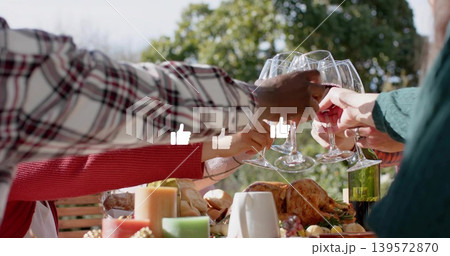 Clinking wine glasses, hands reaching across yard table, turkey, plaid, green sleeves, thumbs-ups Clinking wine glasses, hands reaching across yard table, turkey, plaid, green sleeves, thumbs-ups 139572870