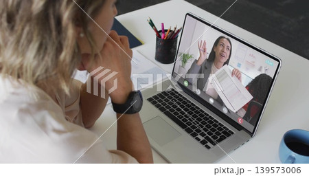 Watching woman wearing blouse and watch leaning on desk, viewing laptop with documents, copy space Watching woman wearing blouse and watch leaning on desk, viewing laptop with documents, copy space 139573006