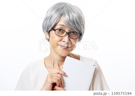 本を持ち老眼鏡をかけた白髪のシニア女性 本を持ち老眼鏡をかけた白髪のシニア女性 139573194