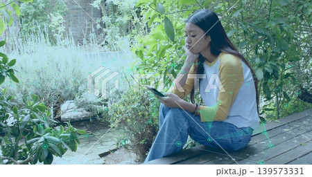 Sitting Asian woman holding smartphone, resting on deck mustard raglan AR overlay, copy space 139573331