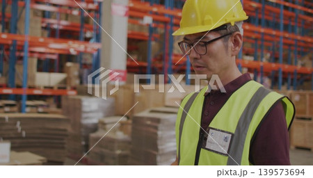 Checking Korean worker in yellow helmet and hi-vis vest inspecting racking at warehouse, copy space Checking Korean worker in yellow helmet and hi-vis vest inspecting racking at warehouse, copy space 139573694