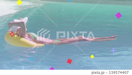 Reclining woman in green bikini, white widebrim hat, floating on yellow ring in pool with overlays 139574407