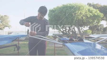 Working woman fixing rigging on blue shell at boatyard wearing gray top red leggings holding wrench 139574530