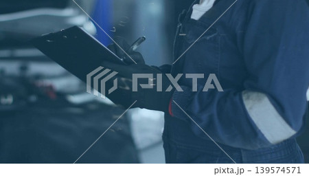 Checking woman mechanic writing on clipboard with pen in garage, open hood, coveralls, gloves Checking woman mechanic writing on clipboard with pen in garage, open hood, coveralls, gloves 139574571