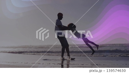 Swinging father holding daughter by hands at ocean shoreline, striped shirt, purple wave overlays Swinging father holding daughter by hands at ocean shoreline, striped shirt, purple wave overlays 139574630