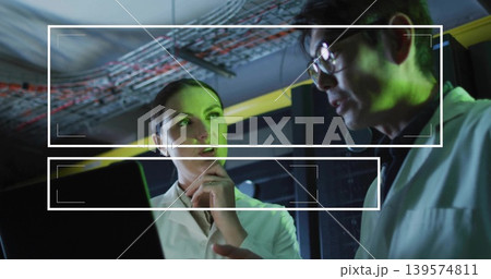 Discussing two lab coat engineers examining laptop in server room, showing yellow cable tray Discussing two lab coat engineers examining laptop in server room, showing yellow cable tray 139574811