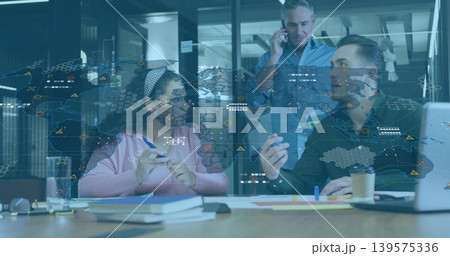 Discussing three colleagues in casual reviewing papers at office with map overlay and smartphone Discussing three colleagues in casual reviewing papers at office with map overlay and smartphone 139575336