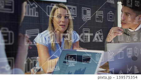 Speaking blonde woman in light blue blouse gesturing in conference room, with laptops and papers 139575354