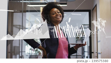 Analyzing analyst in dark blazer pink blouse in office hallway, holding slim laptop with AR charts 139575380