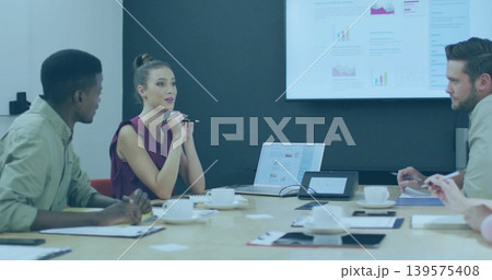 Presenting woman in burgundy sleeveless blouse explaining charts in conference room, with laptop Presenting woman in burgundy sleeveless blouse explaining charts in conference room, with laptop 139575408