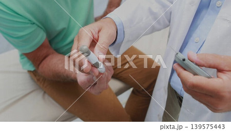 Testing doctor in white-labcoat checking patient in mint polo at exam couch with lancet, glucometer 139575443
