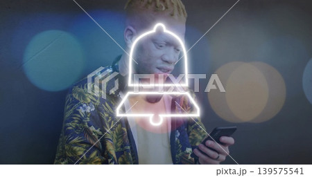 Holding smartphone, man wearing botanical jacket viewing neon bell alert in studio with bokeh Holding smartphone, man wearing botanical jacket viewing neon bell alert in studio with bokeh 139575541