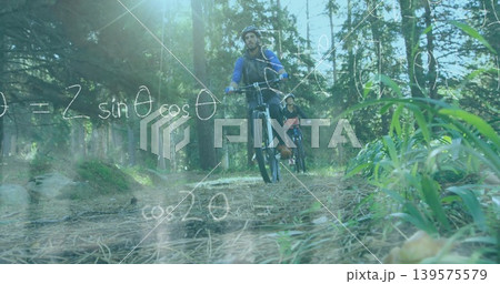 Riding male biker in blue jacket moving along forest trail, with mountain bikes and chalk equations Riding male biker in blue jacket moving along forest trail, with mountain bikes and chalk equations 139575579