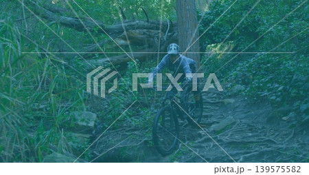 Riding mid-adult man on mountain bike down rooty forest trail, wearing white helmet and jacket Riding mid-adult man on mountain bike down rooty forest trail, wearing white helmet and jacket 139575582