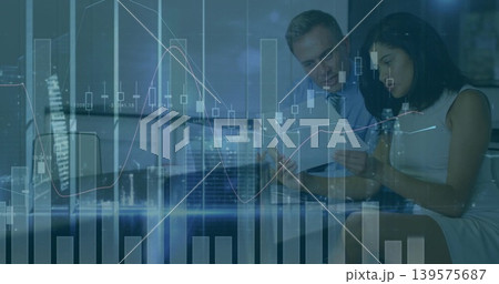 Reviewing pair wearing business attire, studying printed documents in office with screen, charts Reviewing pair wearing business attire, studying printed documents in office with screen, charts 139575687