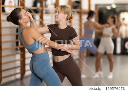Purposeful engrossed women train during self-defense fight training session in gym 139576078