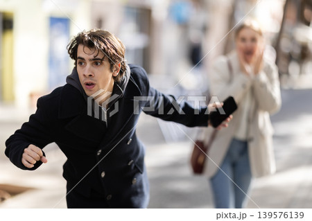 Male thief trying to snatch mobile phone of frightened woman on city Male thief trying to snatch mobile phone of frightened woman on city 139576139