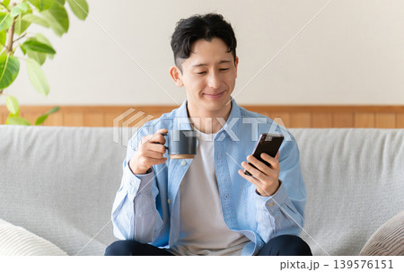 コーヒーを飲みながらスマートフォンを使う男性 コーヒーを飲みながらスマートフォンを使う男性 139576151