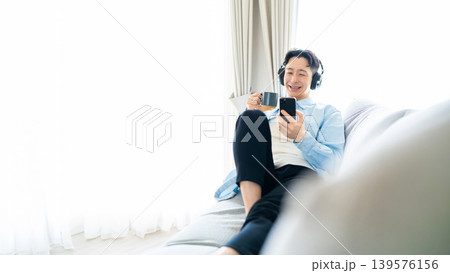 コーヒーを飲みながらスマートフォンを使う男性 139576156