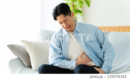 腹痛でお腹を押さえる男性 腹痛でお腹を押さえる男性 139576162