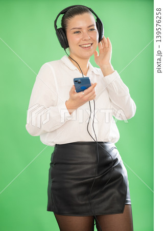 woman listening to music with headphones while scrolling through tracks on mobile 139576258