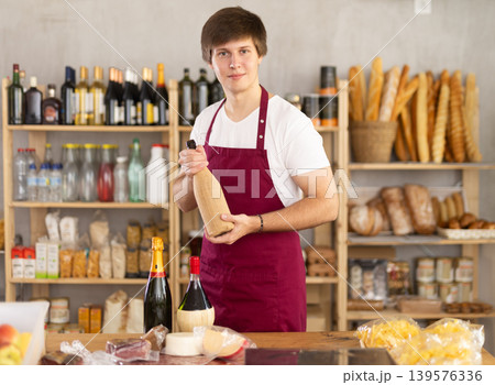 Young salesman offers to buy a bottle of wine in supermarket Young salesman offers to buy a bottle of wine in supermarket 139576336