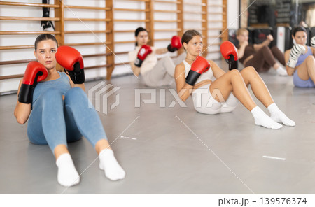 women doing abdominal exercise in boxing gloves women doing abdominal exercise in boxing gloves 139576374
