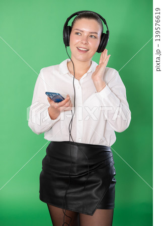 Chroma key compositing. Pretty girl listening to music on headphones on green background 139576619
