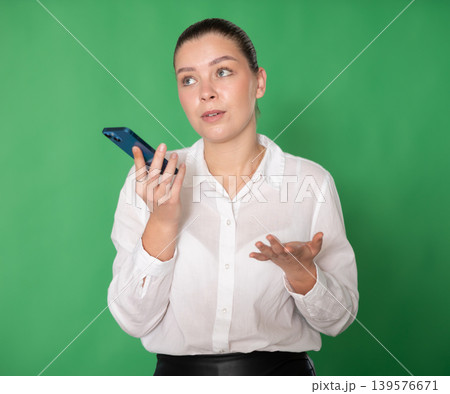 Chroma key compositing. Girl records an audio message on mobile phone Chroma key compositing. Girl records an audio message on mobile phone 139576671