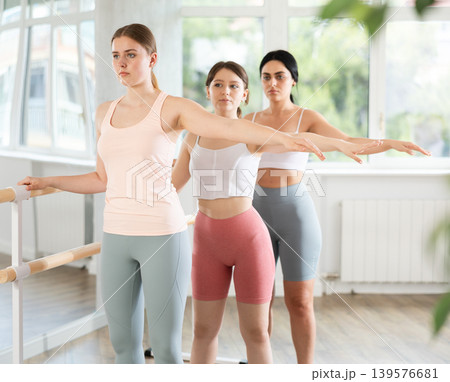 Ballet rehearsal in dance studio - young ballerinas stand in second position near ballet barre 139576681