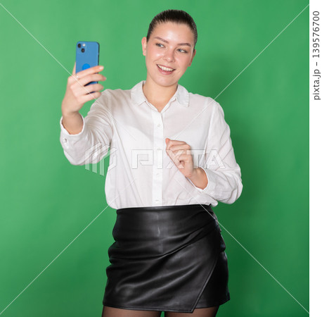 Girl takes selfie on green background Girl takes selfie on green background 139576700