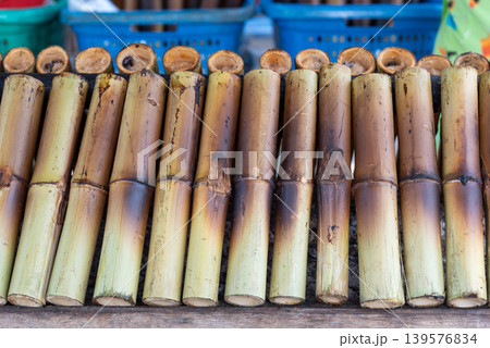 Traditional bamboo sticky rice tubes roasting on charcoal grill at local market showing authentic Asian street food cooking and rustic texture Traditional bamboo sticky rice tubes roasting on charcoal grill at local market showing authentic Asian street food cooking and rustic texture 139576834