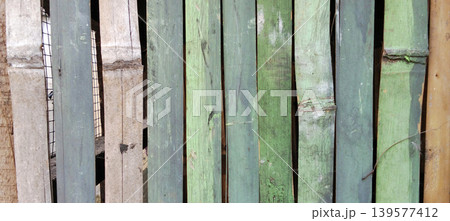 A close-up of a row of dark green wooden planks with a rough texture and faded paint. A close-up of a row of dark green wooden planks with a rough texture and faded paint. 139577412