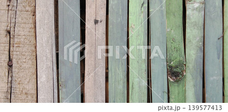 A close-up of a row of dark green wooden planks with a rough texture and faded paint. 139577413