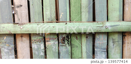 A close-up of a row of dark green wooden planks with a rough texture and faded paint. A close-up of a row of dark green wooden planks with a rough texture and faded paint. 139577414